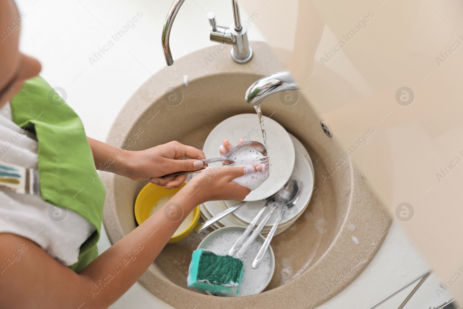 Photo of Woman doing washing up in kitchen sink. Cleaning chores