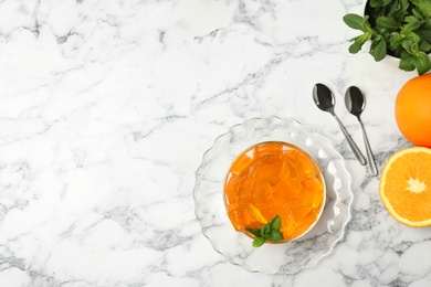 Flat lay composition with orange jelly in  bowl on marble table. Space for text