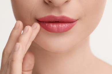 Photo of Young woman with beautiful full lips on white background, closeup