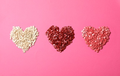 Photo of Hearts made with sprinkles on pink background, flat lay