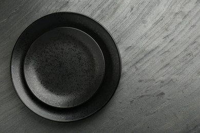 Photo of Beautiful ceramic plates on black table, top view. Space for text