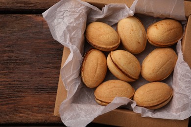 Delicious nut shaped cookies with boiled condensed milk in box on wooden table, top view