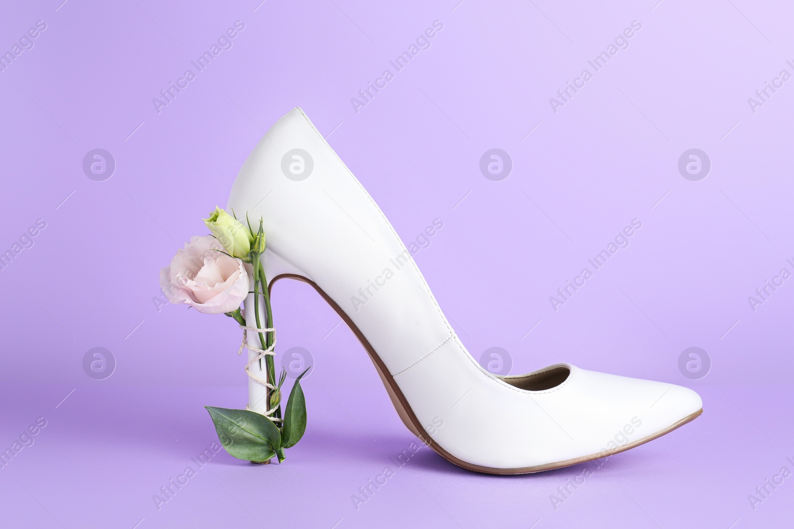 Photo of Stylish women's high heeled shoe with beautiful flower on violet background