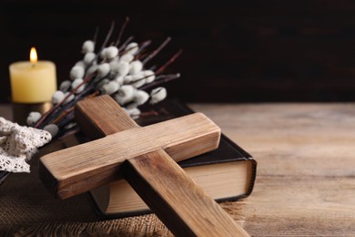 Photo of Cross, Bible and willow branches on wooden table, closeup. Space for text