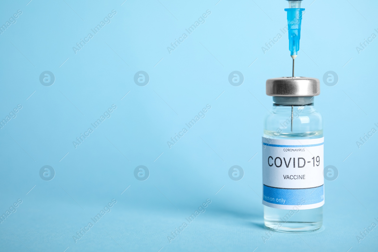 Photo of Filling syringe with coronavirus vaccine on light blue  background, space for text