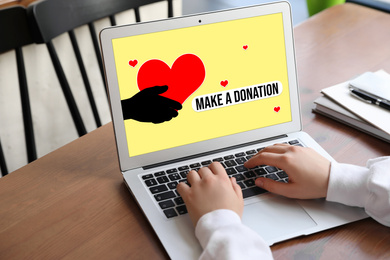 Image of Donations concept. Woman with laptop at wooden table, closeup