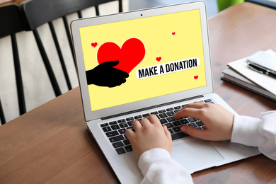 Donations concept. Woman with laptop at wooden table, closeup