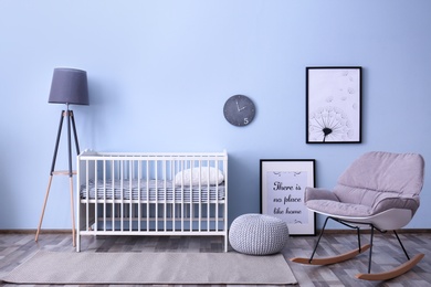 Photo of Baby room interior with crib and rocking chair near wall
