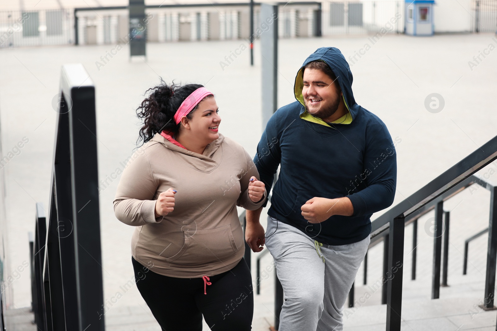 Photo of Overweight couple running up stairs together outdoors