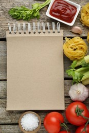 Blank recipe book and different ingredients on wooden table, flat lay. Space for text