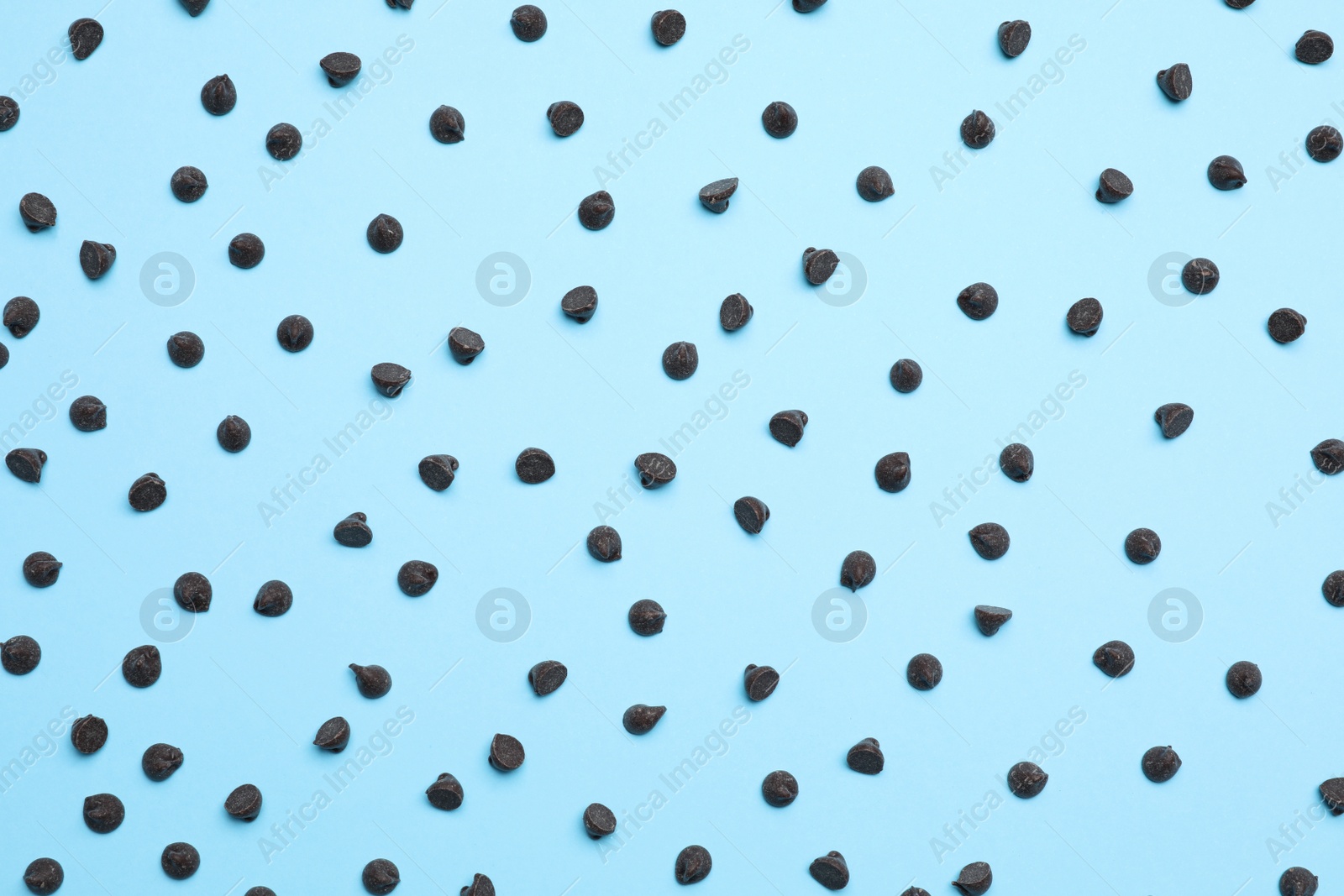 Photo of Delicious dark chocolate chips on light blue background, top view