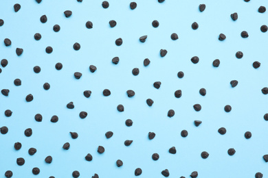 Delicious dark chocolate chips on light blue background, top view