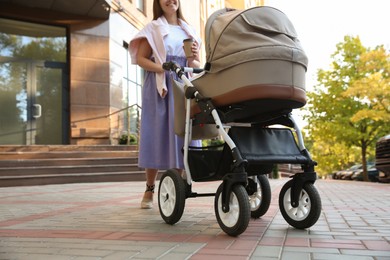 Young mother walking with her baby in stroller outdoors, closeup