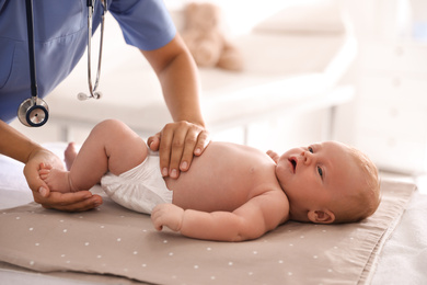 Photo of Doctor examining cute baby in clinic, closeup. Health care