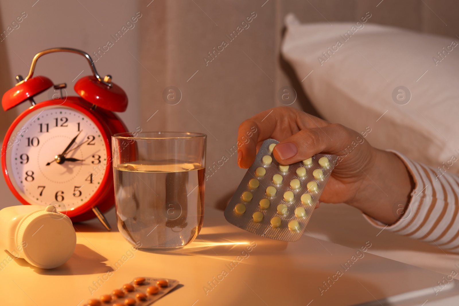 Photo of Woman taking pills from nightstand in bedroom at night, closeup. Insomnia concept