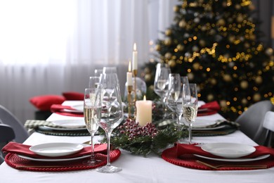 Photo of Christmas table setting with festive decor and dishware indoors