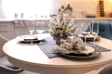 Photo of Table with set of dishware and beautiful Christmas decor in kitchen. Interior design