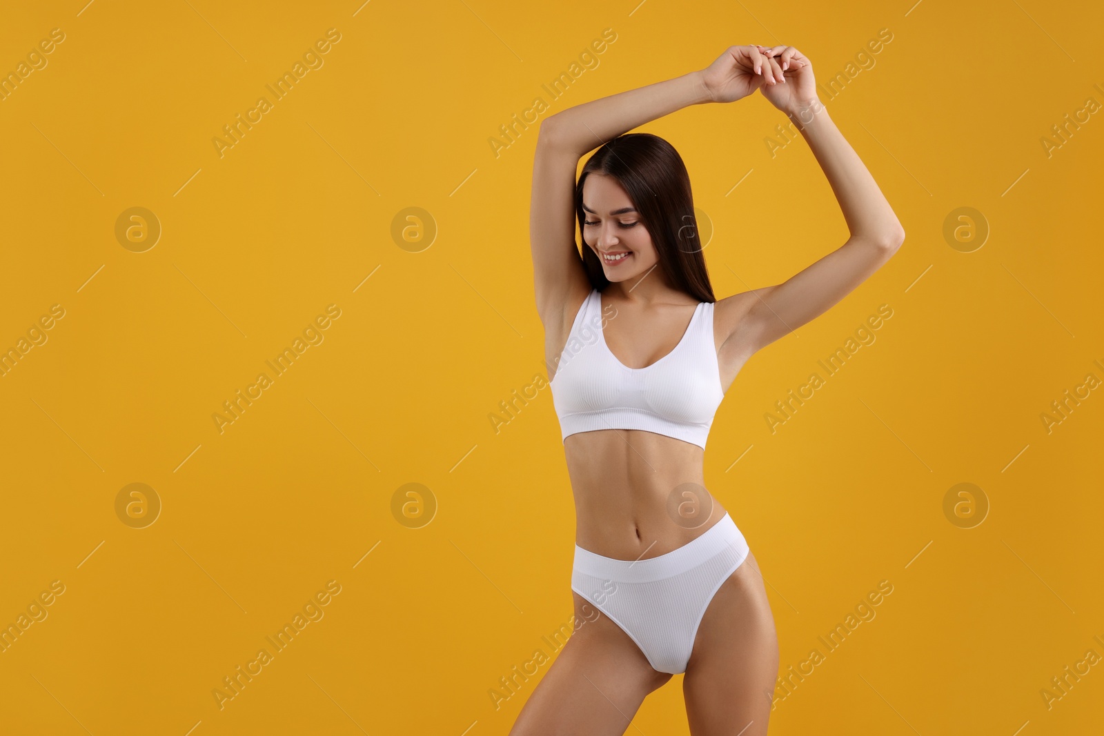 Photo of Young woman in stylish white bikini on orange background. Space for text