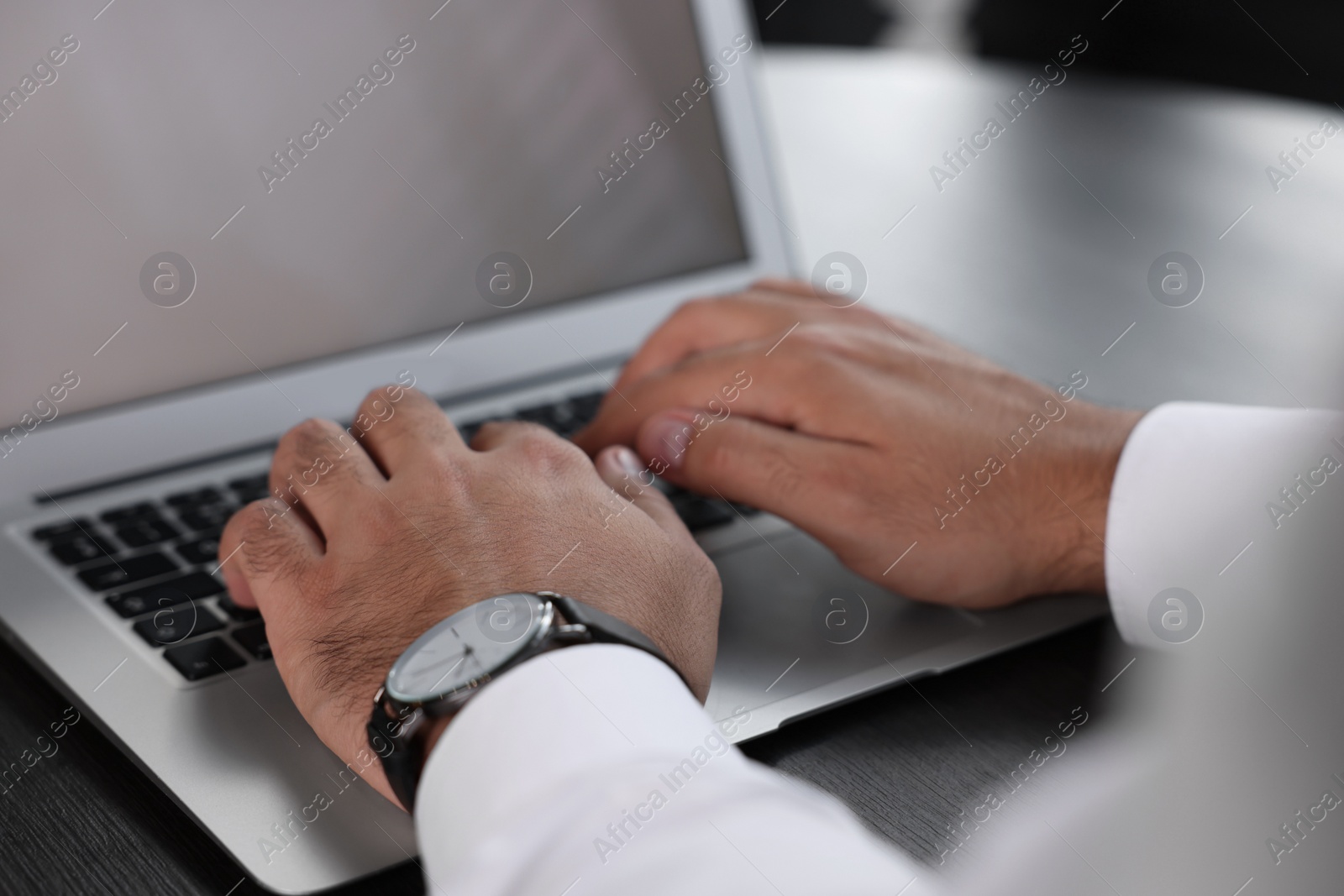Photo of Man working on laptop at table indoors, closeup