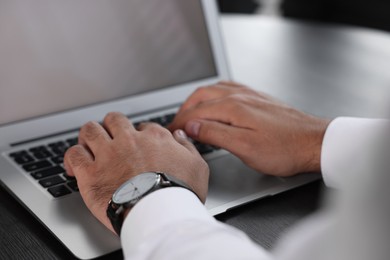 Man working on laptop at table indoors, closeup