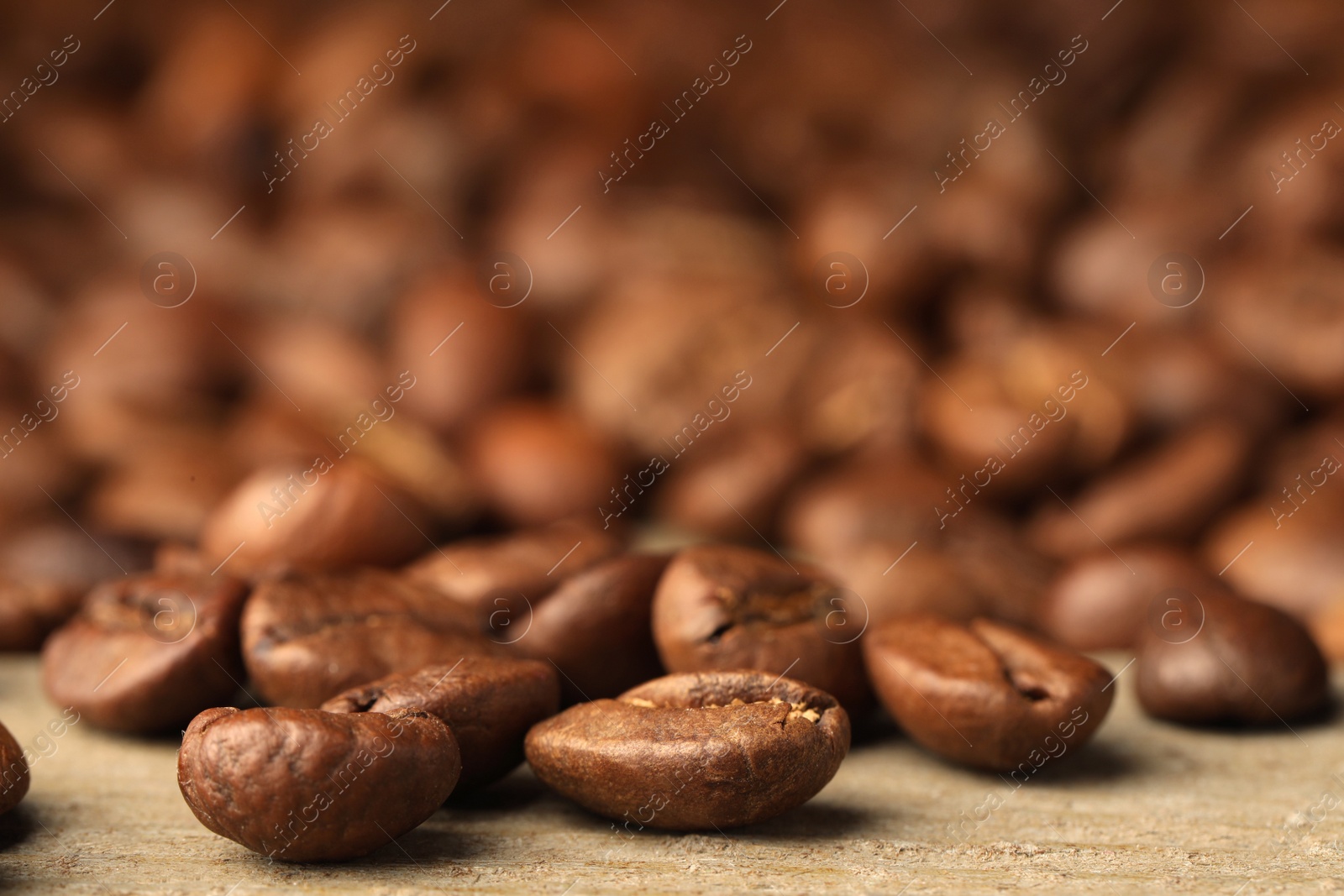 Photo of Many roasted coffee beans on wooden table, closeup