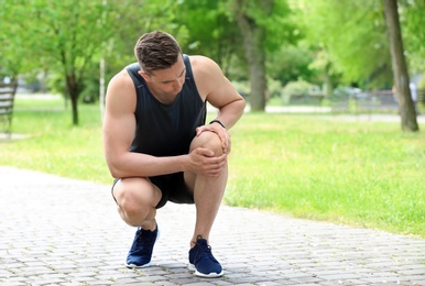 Photo of Man in sportswear suffering from knee pain outdoors