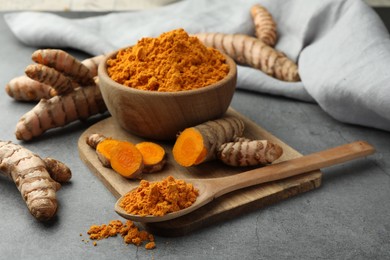 Photo of Aromatic turmeric powder and raw roots on grey table