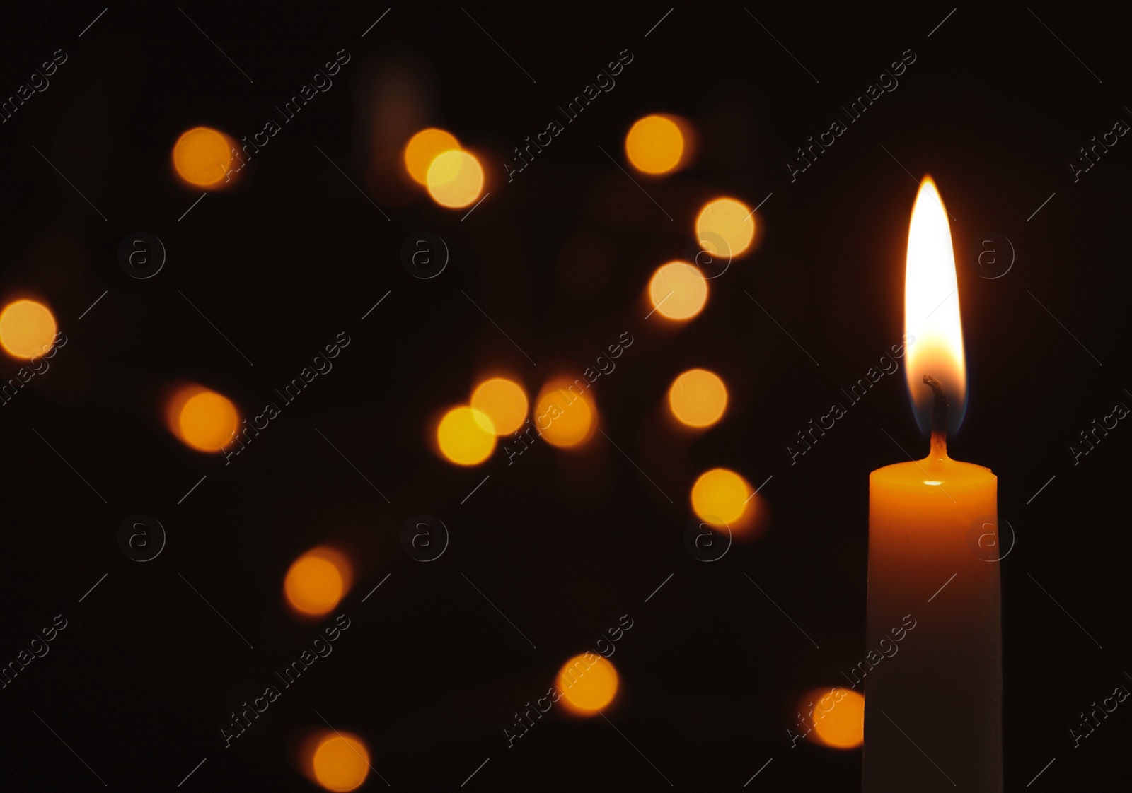 Photo of Wax candle burning on blurred background, closeup