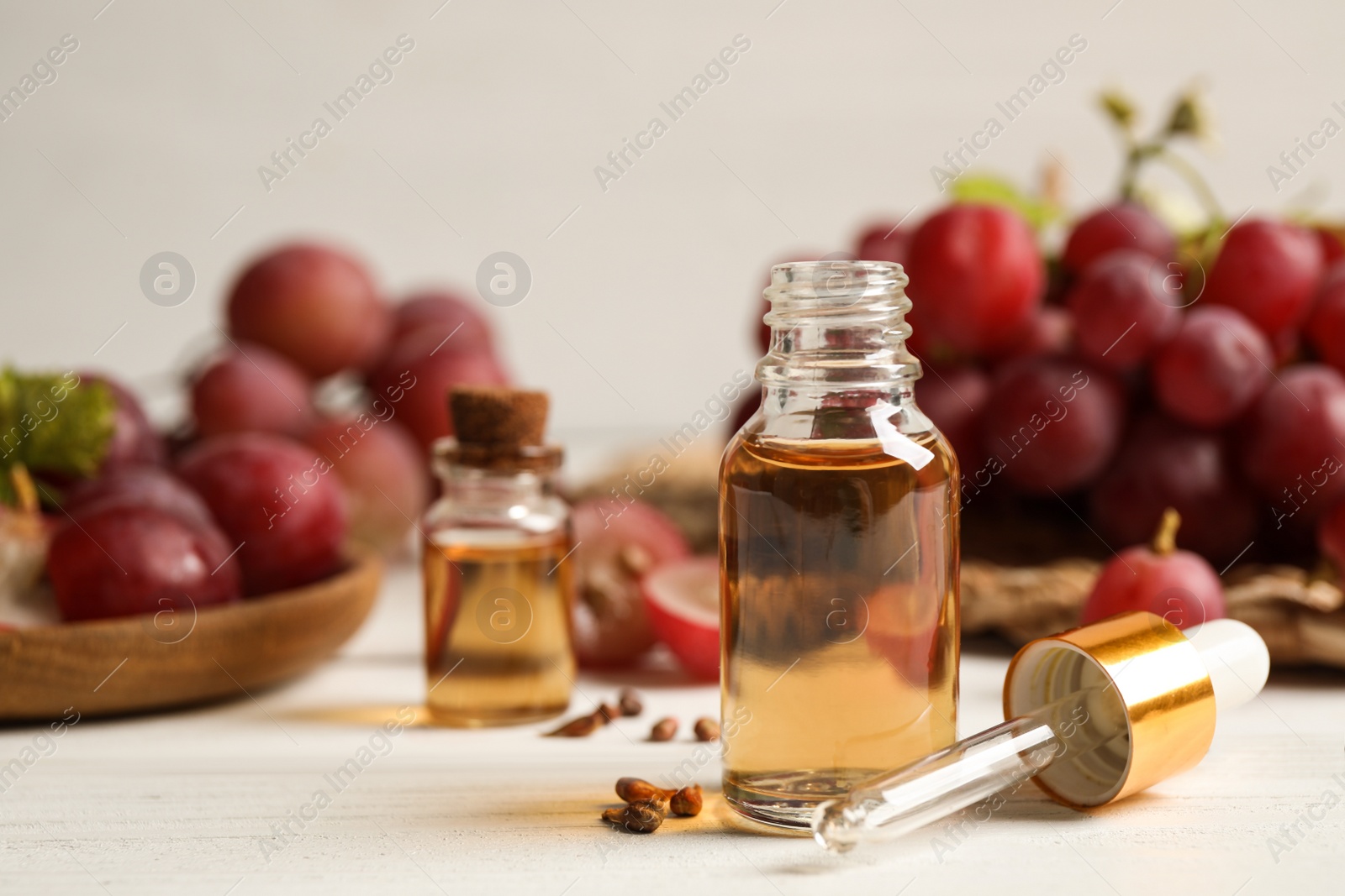 Photo of Bottle of natural grape seed oil on white wooden table. Organic cosmetic