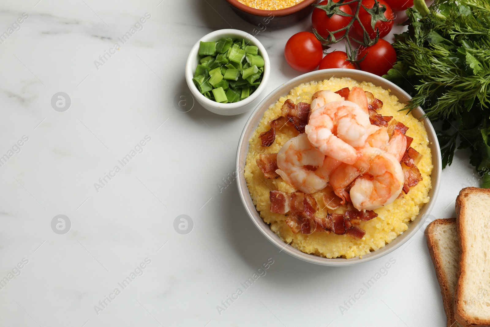 Photo of Fresh tasty shrimps, bacon and grits in bowl on white marble table, flat lay. Space for text