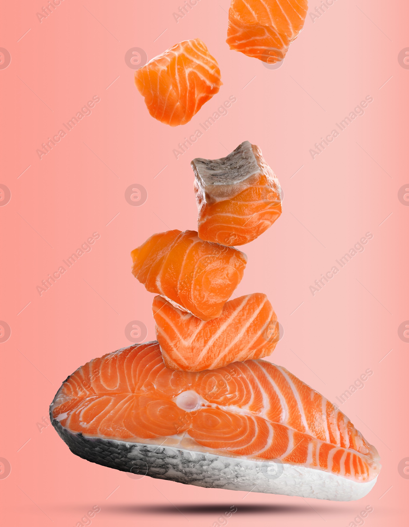 Image of Cut fresh salmon falling on pink background