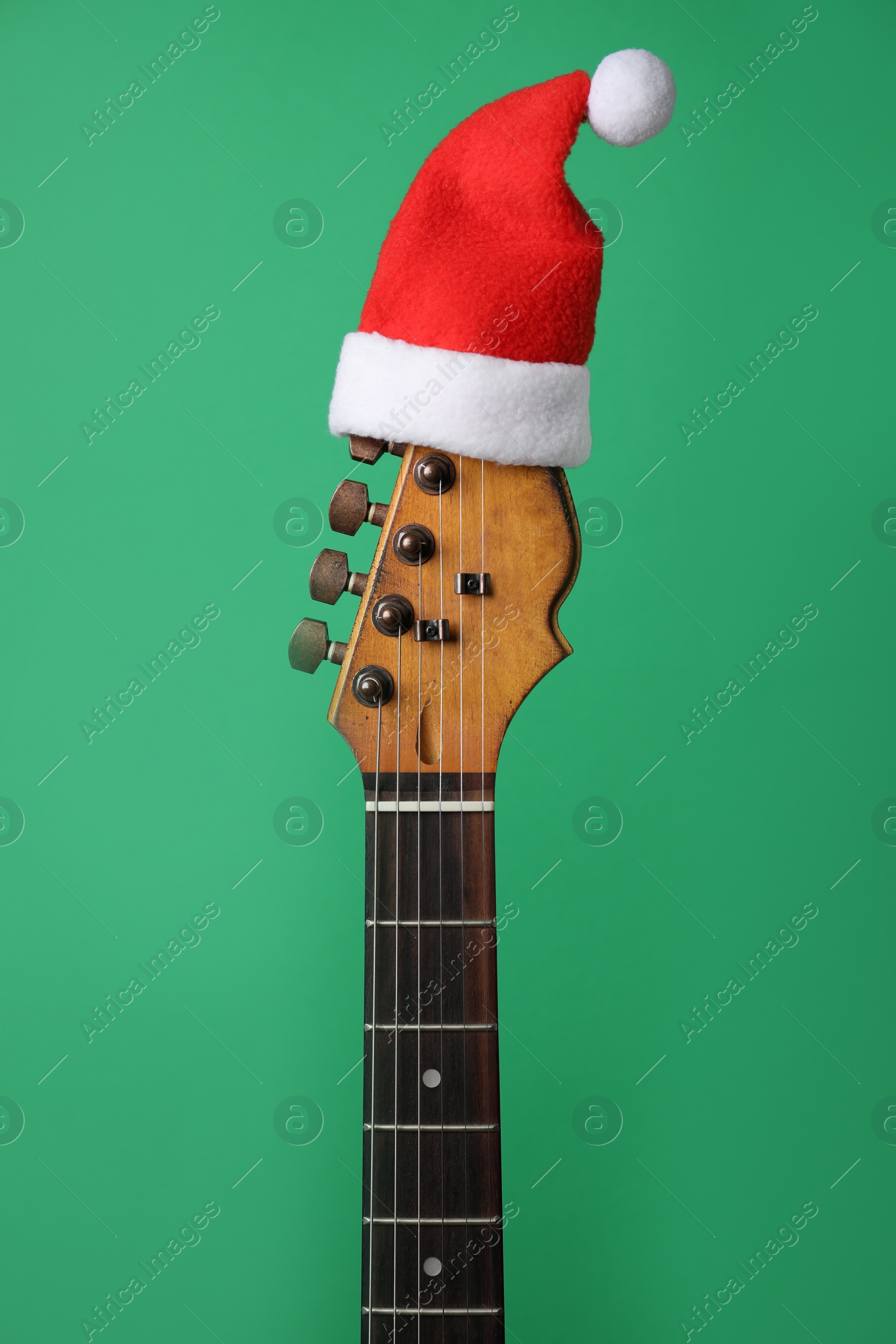 Photo of Guitar with Santa hat on green background. Christmas music concept
