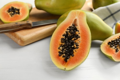 Photo of Fresh ripe papaya fruits on white wooden table. Space for text