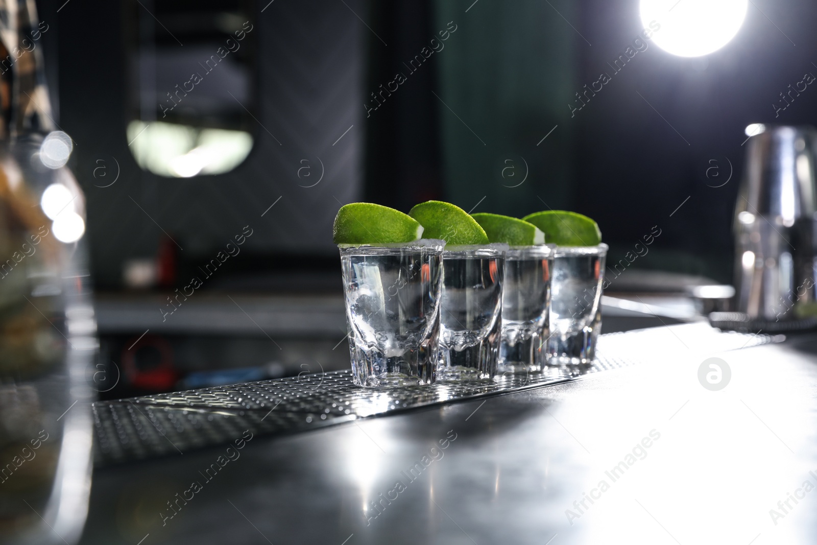 Photo of Mexican Tequila shots with lime slices on bar counter