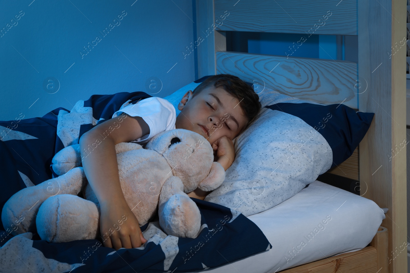 Photo of Cute little boy sleeping with teddy bear at home. Bedtime