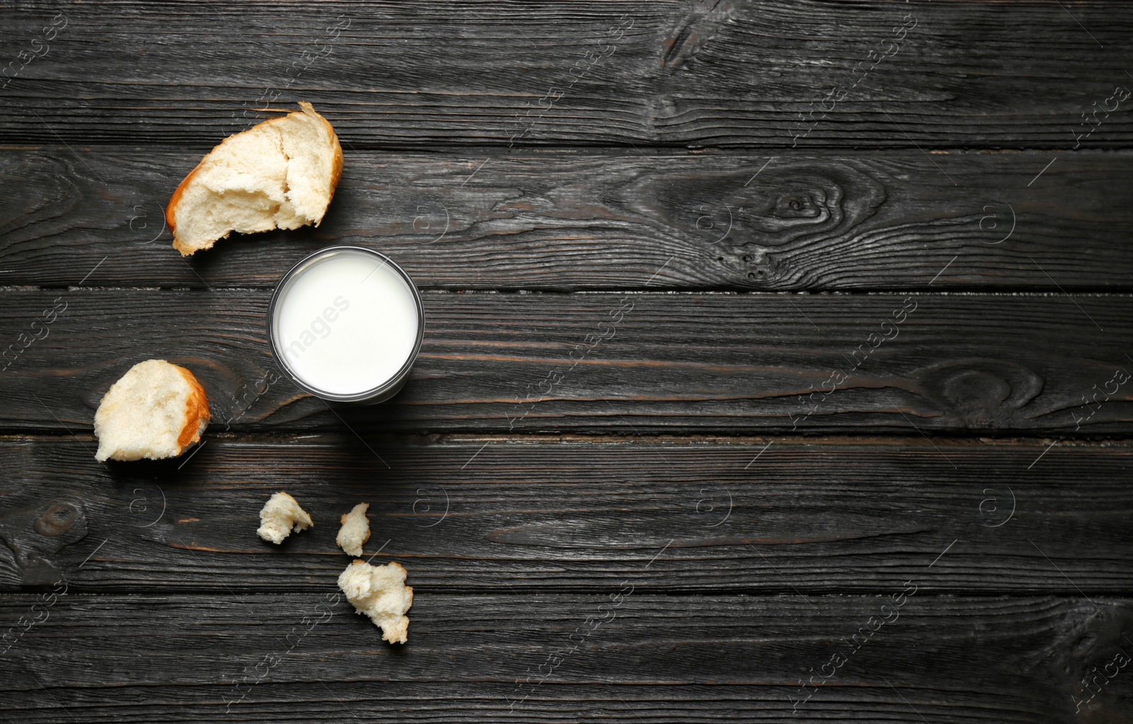 Photo of Glass of milk and bun pieces on wooden background, top view