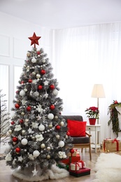 Photo of Beautiful Christmas tree with star topper in decorated room