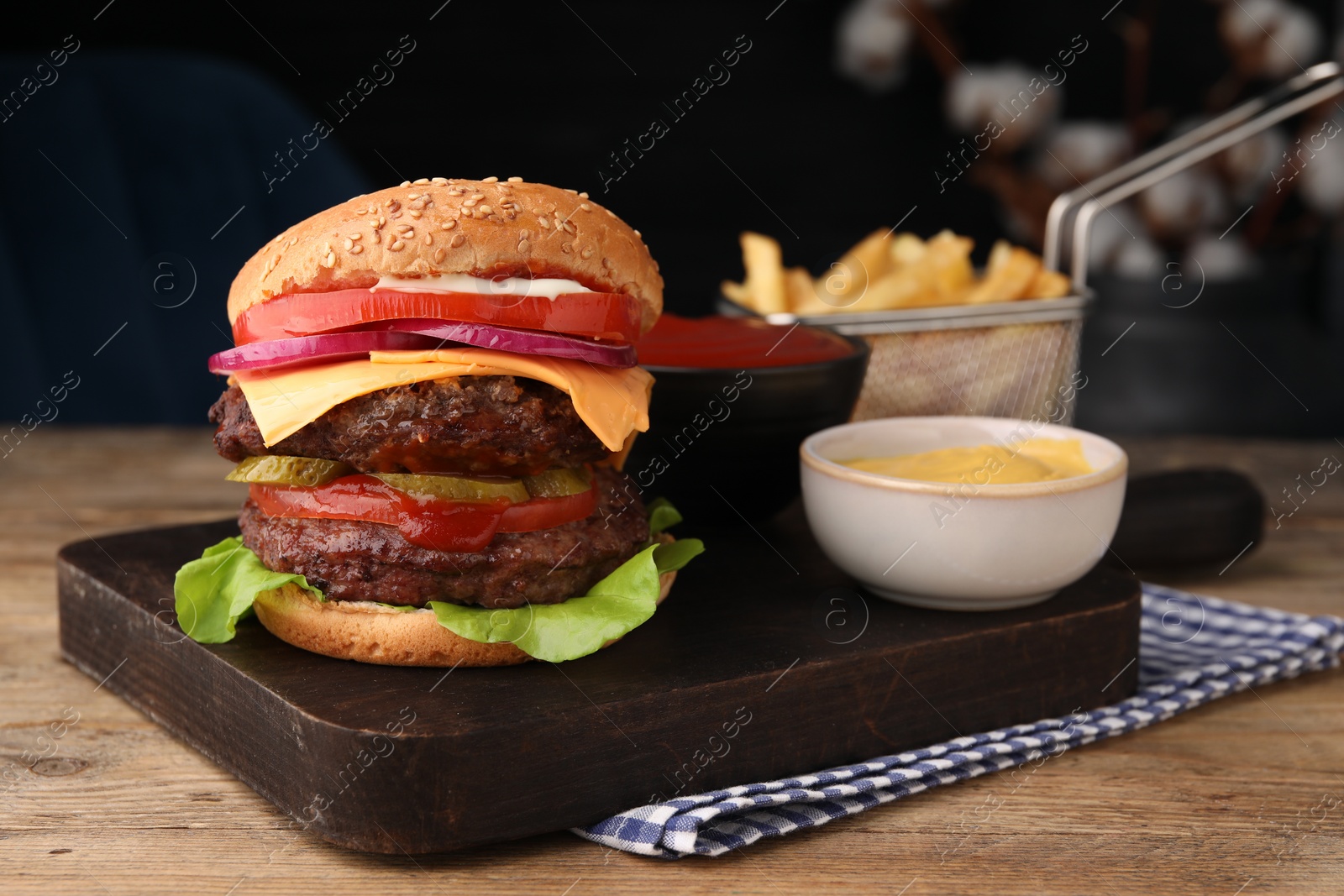 Photo of Tasty cheeseburger with patties, tomato and sauce on wooden table