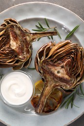 Plate with tasty grilled artichoke on table, top view