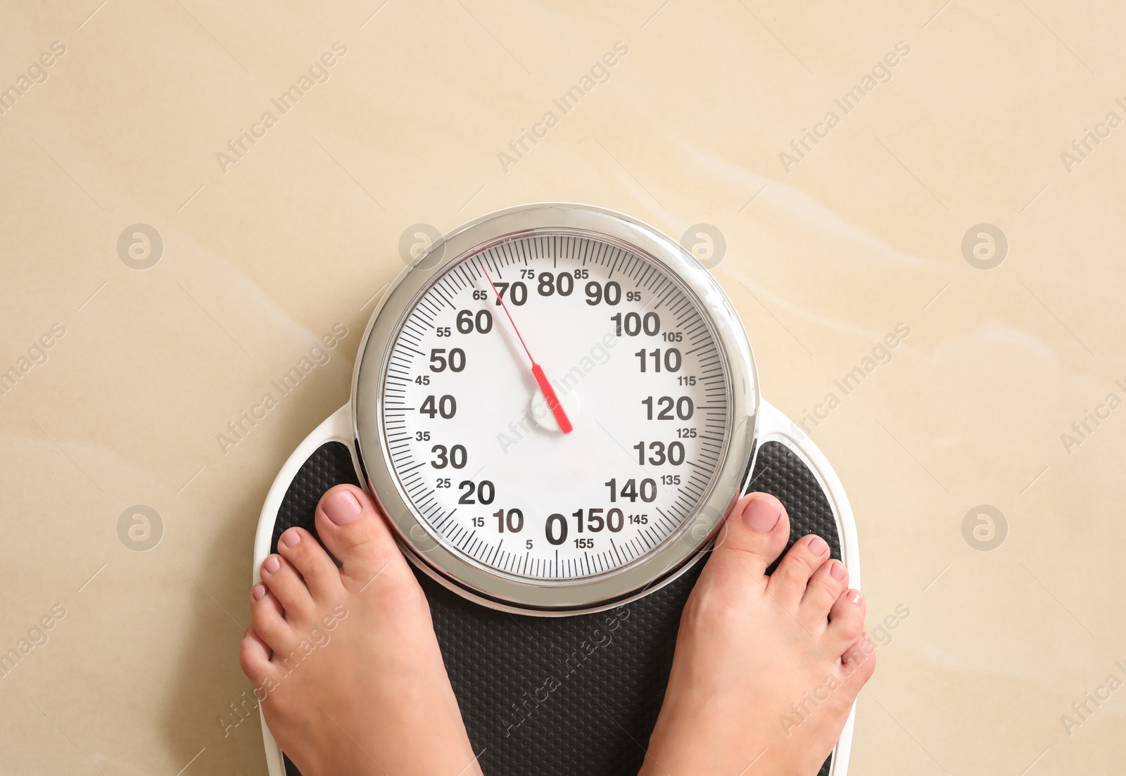 Photo of Woman standing on floor scales indoors, top view. Overweight problem