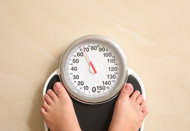 Woman standing on floor scales indoors, top view. Overweight problem