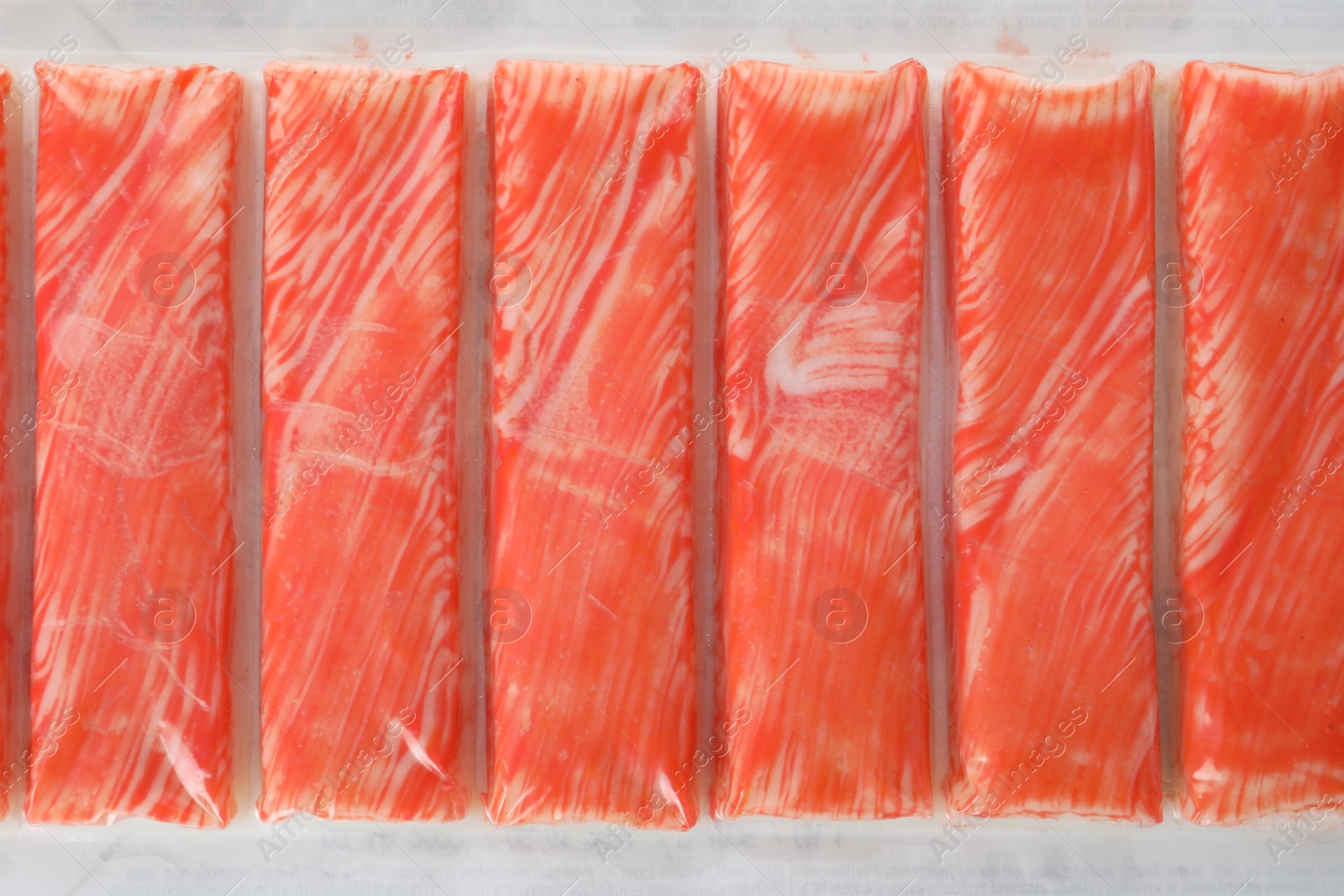 Photo of Top view on fresh crab sticks in pack as background, closeup