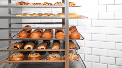 Photo of Rack with fresh pastries in bakery workshop. Space for text