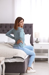 Photo of Young woman suffering from back pain at home