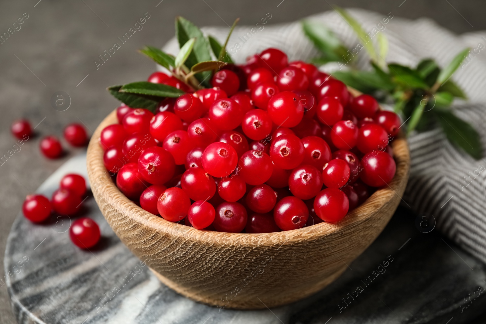 Photo of Tasty ripe cranberries on grey marble board, closeup