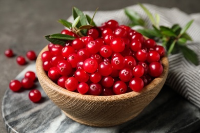 Tasty ripe cranberries on grey marble board, closeup