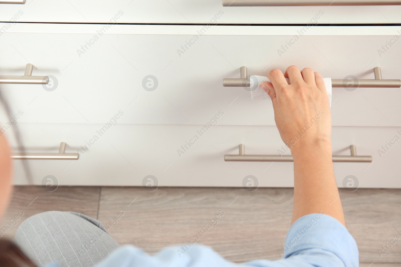 Photo of Woman using tissue paper to open drawer, closeup