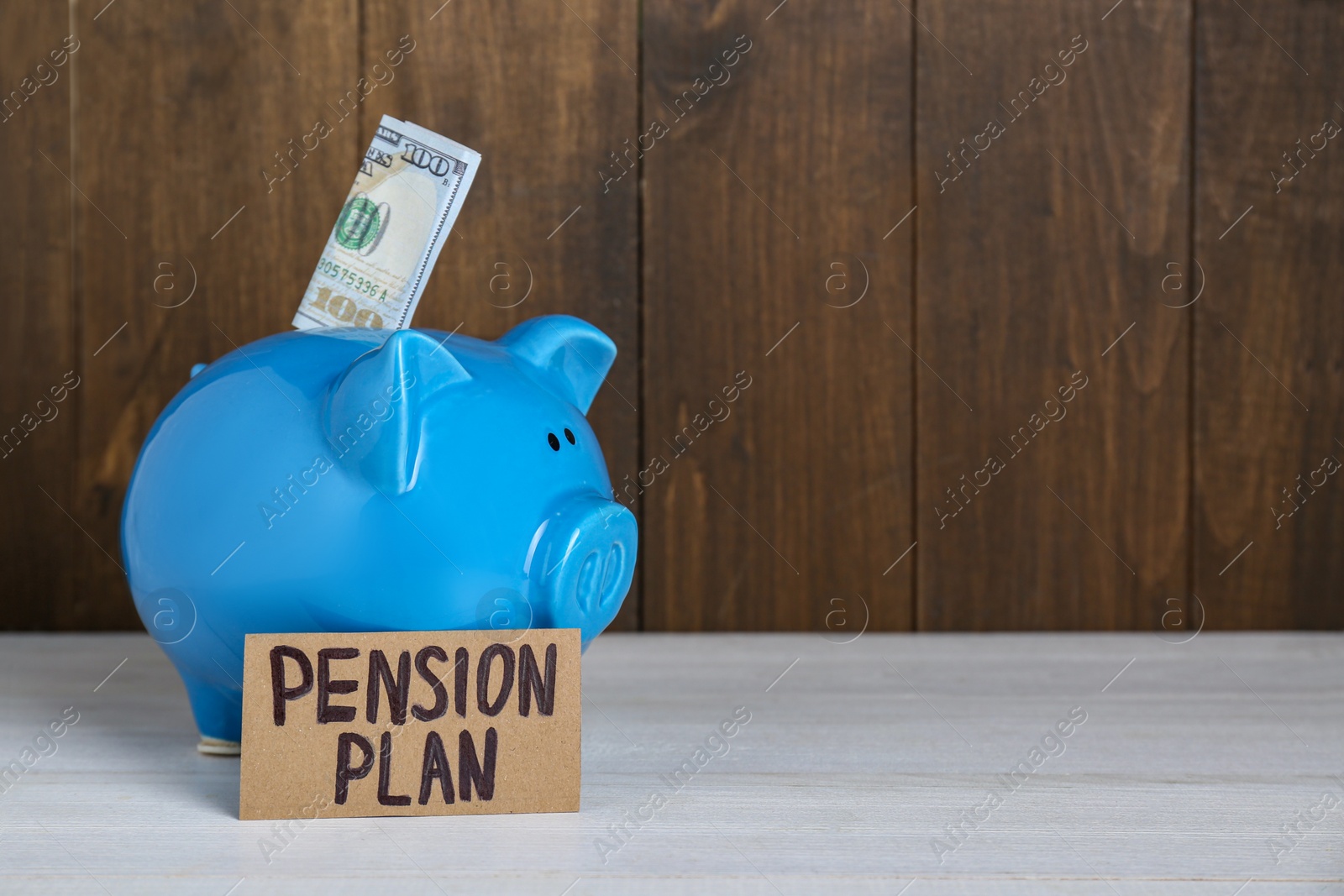Photo of Card with phrase Pension Plan, piggy bank and dollar banknote on white wooden table, space for text. Retirement concept