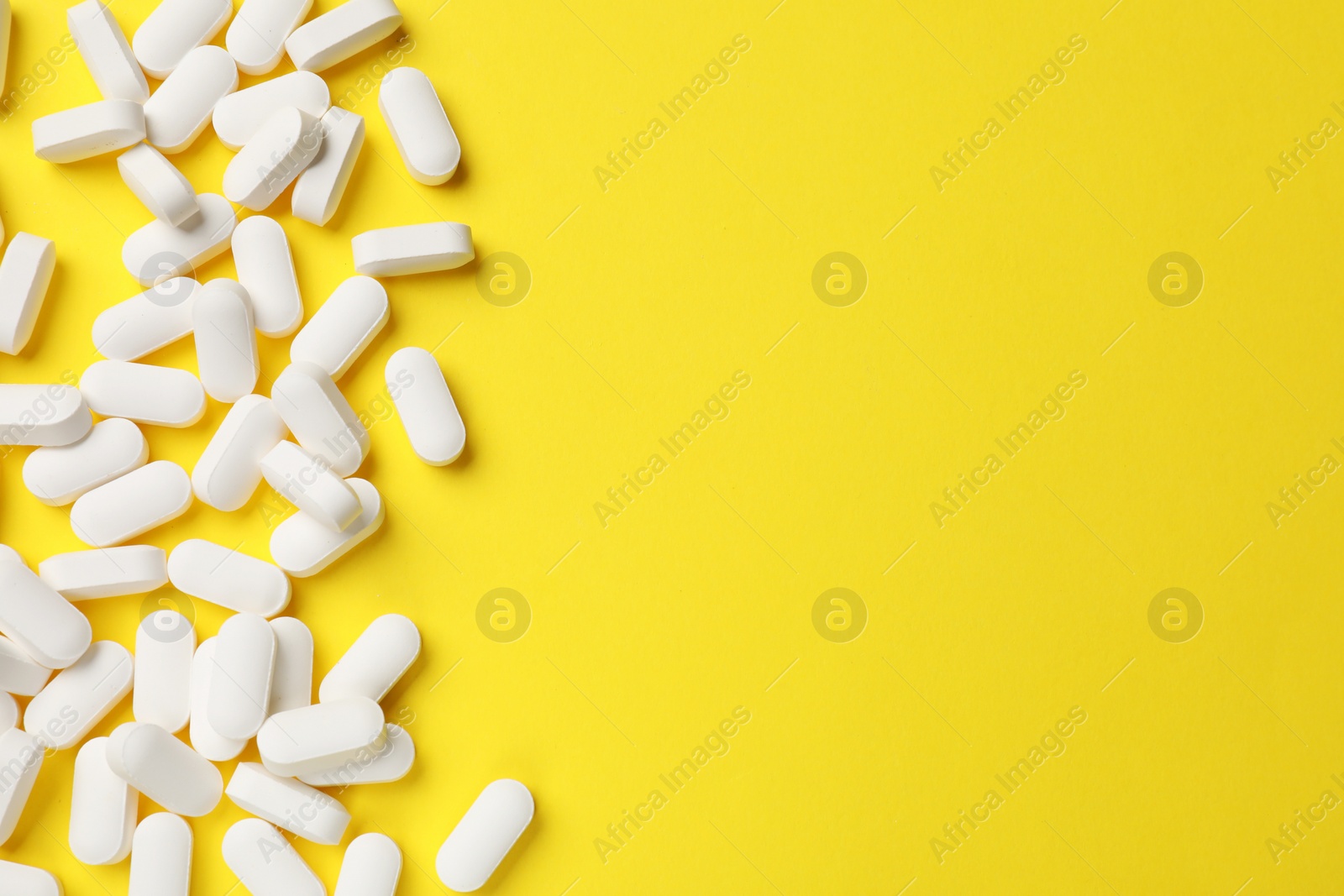 Photo of Vitamin pills on yellow background, flat lay. Space for text