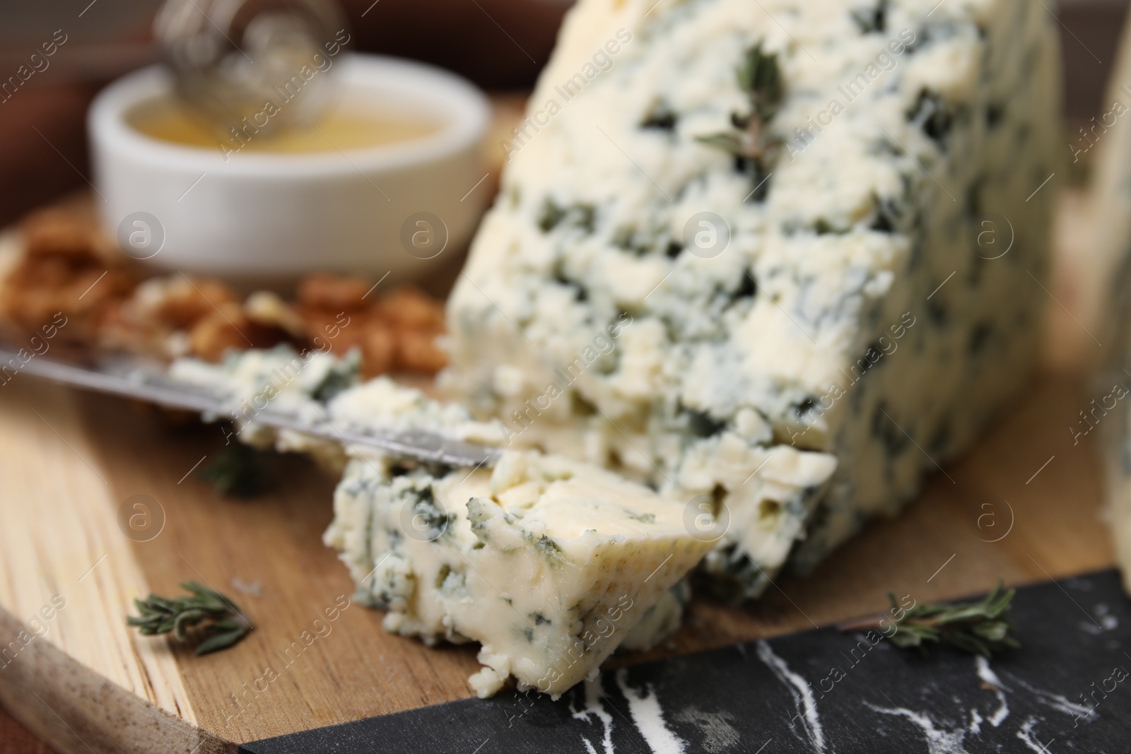 Photo of Tasty blue cheese with thyme and knife on wooden board, closeup